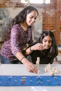 A mother and daughter enjoy creative play with wooden blocks indoors, enhancing family bonding and learning.